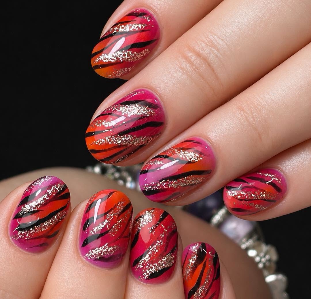 Pink and orange nail art with black stripes and glitter